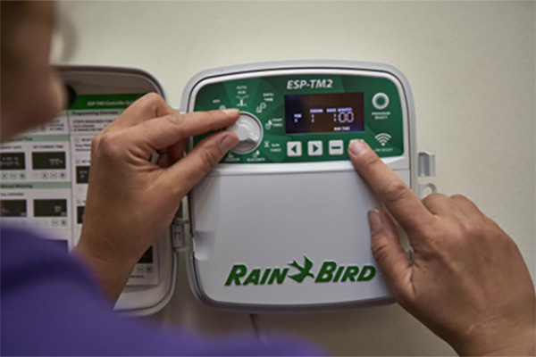 A person adjusting their smart irrigation controller