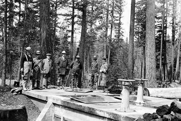 historic image of the completion of the Big Butte Springs Pipeline and people standing around it.